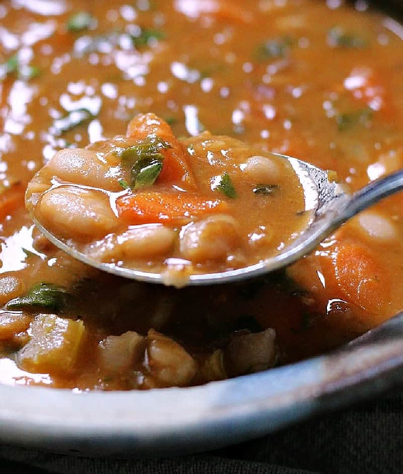 bowl of Bean with Bacon Soup and spoon scooping some out