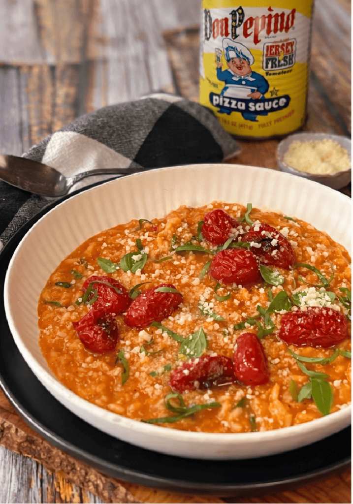 shallow white bowl with roasted tomato risotto garnished with basil leaves