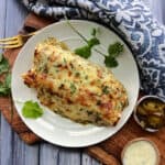 overhead view - white plate with green chicken enchiladas with side of pickled jalapenos
