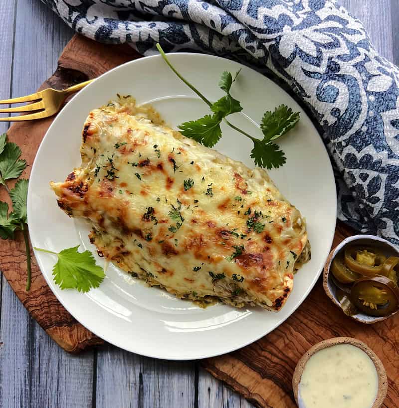 overhead view - white plate with green chicken enchiladas with side of pickled jalapenos