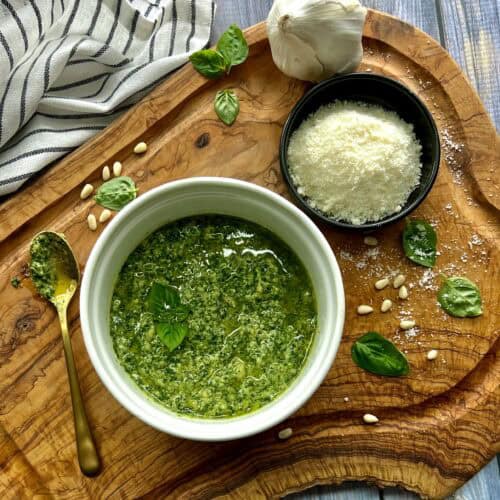overhead view - basil pesto, small dish of parmesan cheese and basil leaves