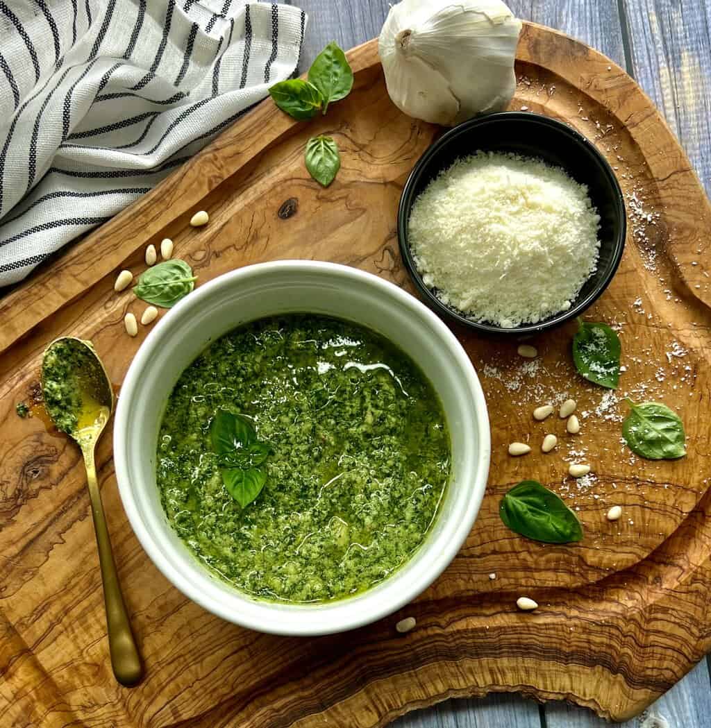 overhead view - basil pesto, small dish of parmesan cheese and basil leaves