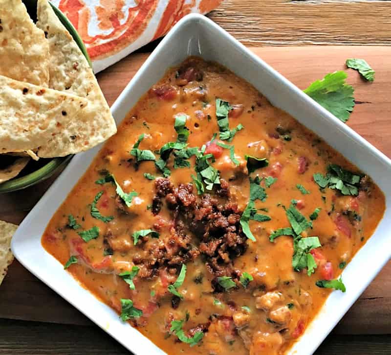 overhead view - white bowl with chorizo queso dip garnished with finely chopped cilantro and a crumbled or cooked chorizo