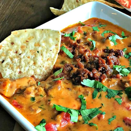 white bowl with chorizo queso garnished with cilantro and a spoonful of chorizo