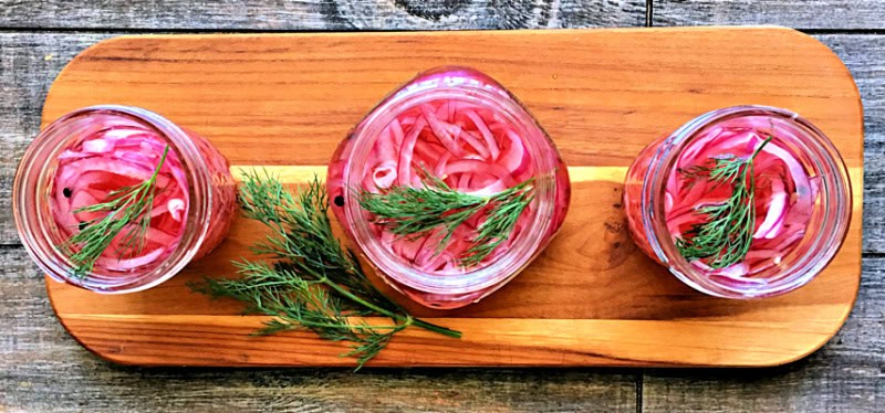 overhead view pickled red onions in mason jars on wood board