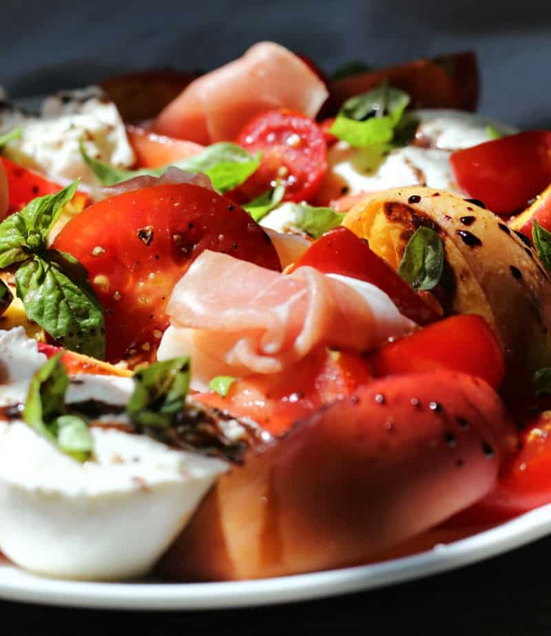 closeup of grilled peach caprese salad with prosciutto