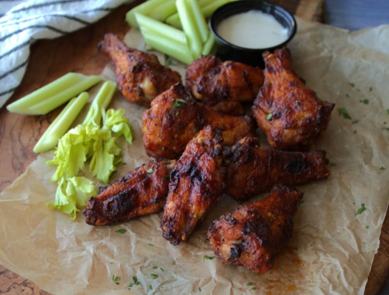 overhead view of crispy baked wings with cut celery pieces and ranch dip