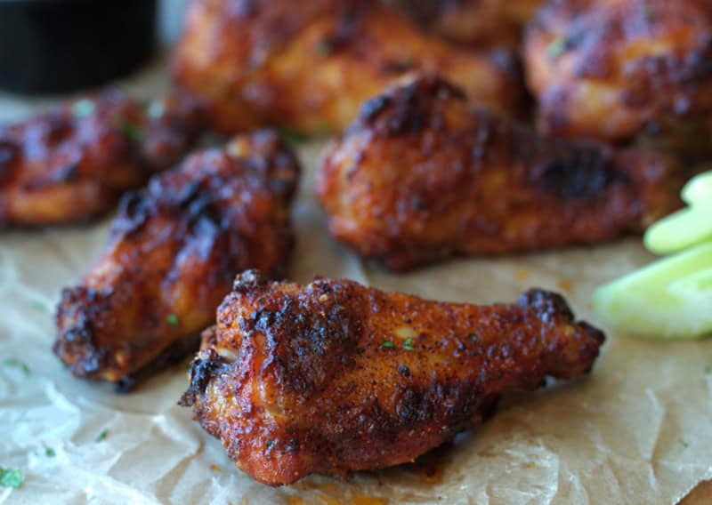 crispy baked wings on parchment paper with small bowl of ranch for dipping