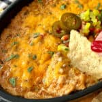 black casserole dish with beef enchilada dip garished with pickled jalapenos