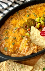 black casserole dish with beef enchilada dip garished with pickled jalapenos