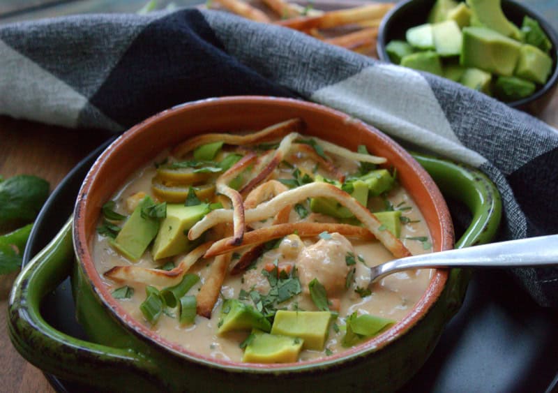 green bowl with slow cooker white chicken chili garnished with crispy tortilla strips