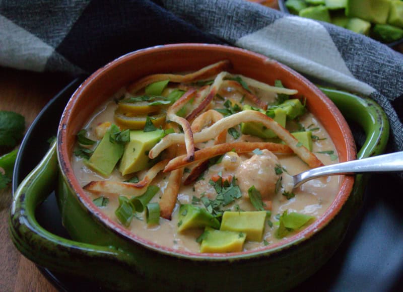 green bowl with slow cooker white chicken chili and spoon scooping some out