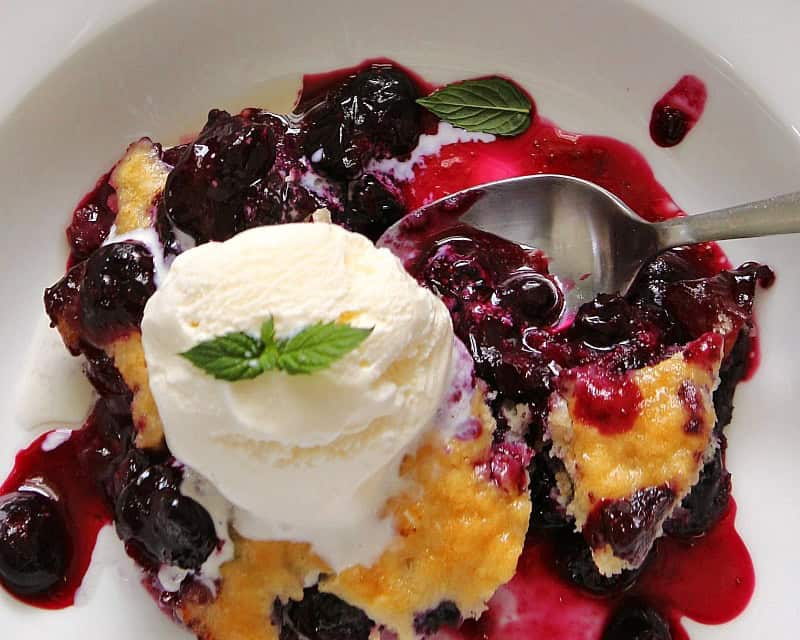 overhead view blueberry cobbler with ice cream and mint leaf garnish