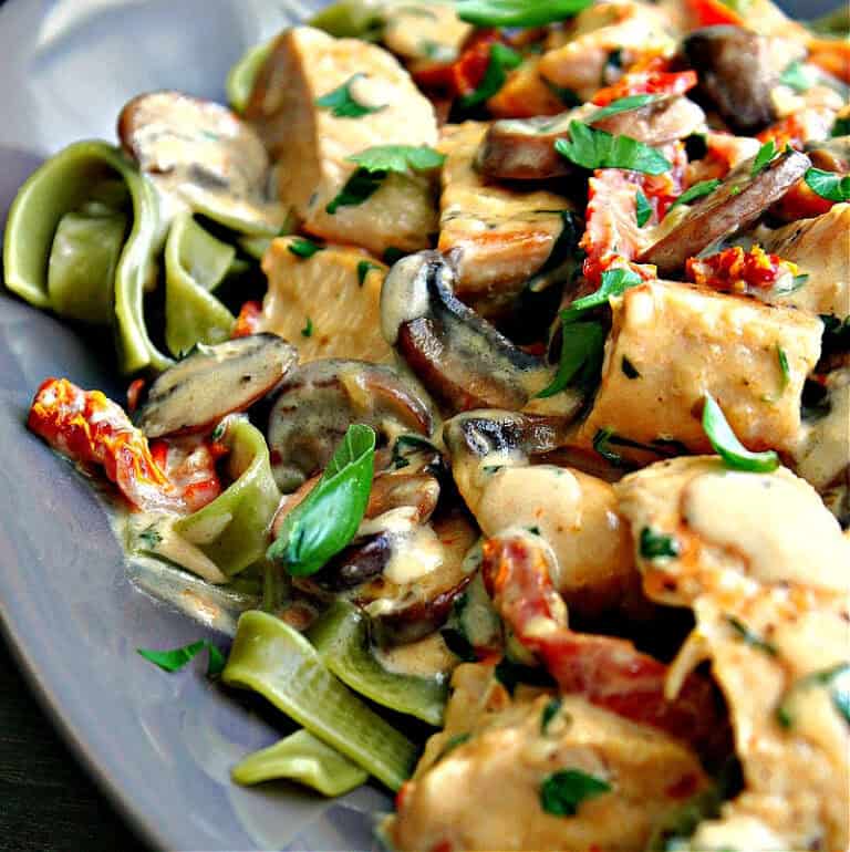 gray plate with marry me chicken pasta with sun dried tomatoes and mushrooms and spinach fettucine