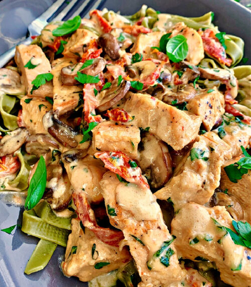 overhead view - gray plate with marry me chicken pasta with spinach fettucine and garnished with fresh basil leaves