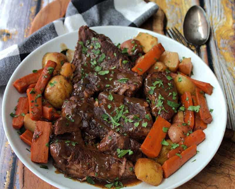 white platter with slow cooker pot roast, carrots and potatoes