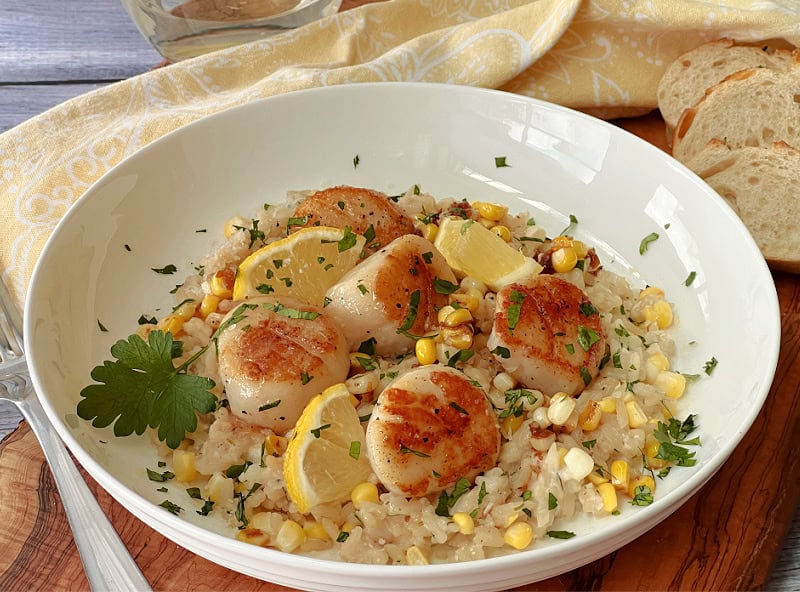 shallow white bowl with corn risotto and pan seared scallops