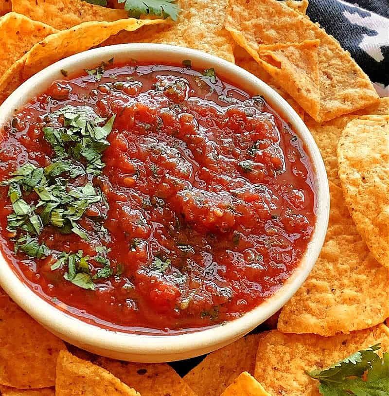 overhead view of refrigerator salsa in a white bowl garnished with minced cilantro