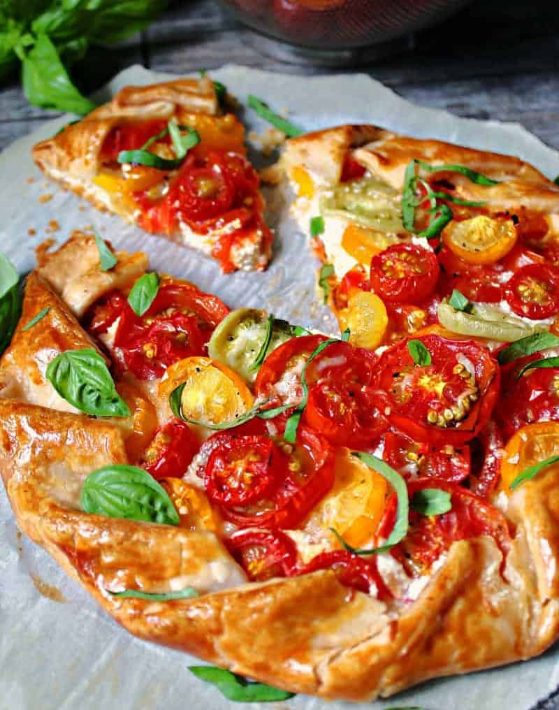 sliced tomato galette with one piece pulled out to show goat cheese
