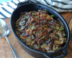 small black casserole with green bean casserole for two topped with fresh caramelized onions