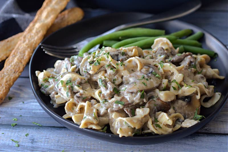 black plate with hamburger helper beef stroganoff and green beans
