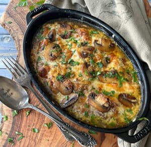 black casserole dish with cheesy baked chicken with mushrooms