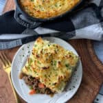 White place with slice of Shepherd's Pie, casserole dish in the background