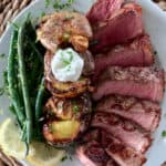 how to cook ribeye without a cast iron skillet. sliced steak shown with potatoes and smashed potatoes