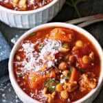 white bowl with turkey lentil soup garnished with grated parmesan cheese