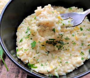 black bowl with creamy parmesan rice and fork lifting a bite out