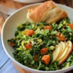 white bowl with fall kale salad and wedge of crusty bread.