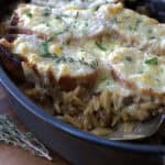 black casserole dish with French Onion Soup Casserole topped with melty cheese