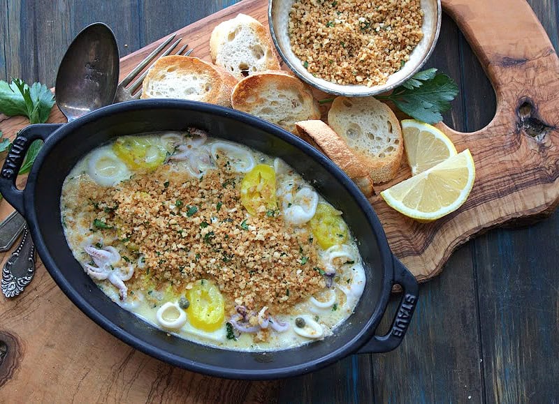 overhead view black serving dish with sauteed calamari topped with golden breadcrumbs