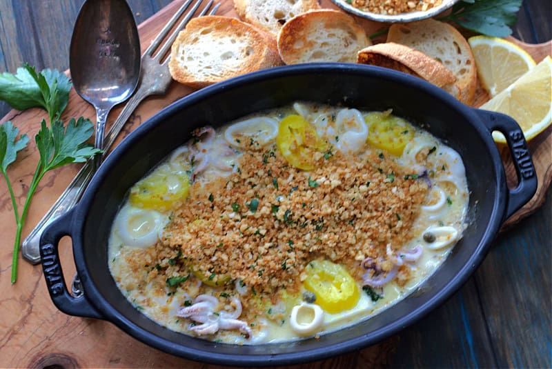 black serving dish with sauteed calamari topped with golden breadcrumbs