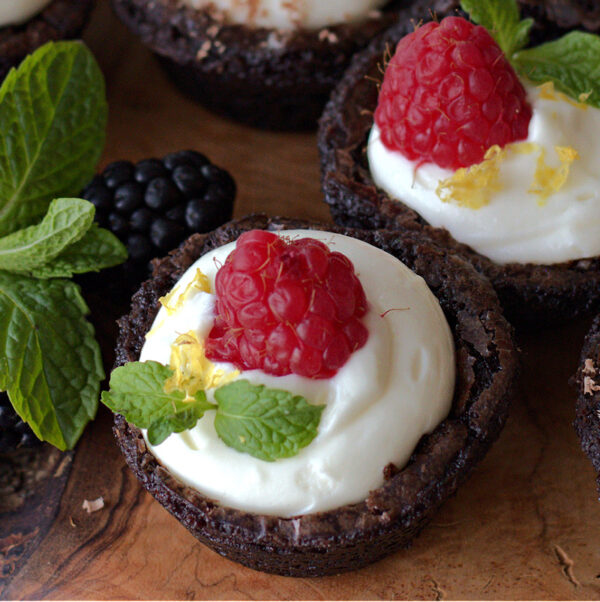 Cheesecake Brownie Bite topped with a single raspberry and mint leaf