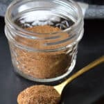 glass jar with taco seasoning and spoonful of seasoning in front of it
