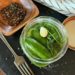 overhead view - refrigerator dill pickles in mason jar with fresh dill sprig on top
