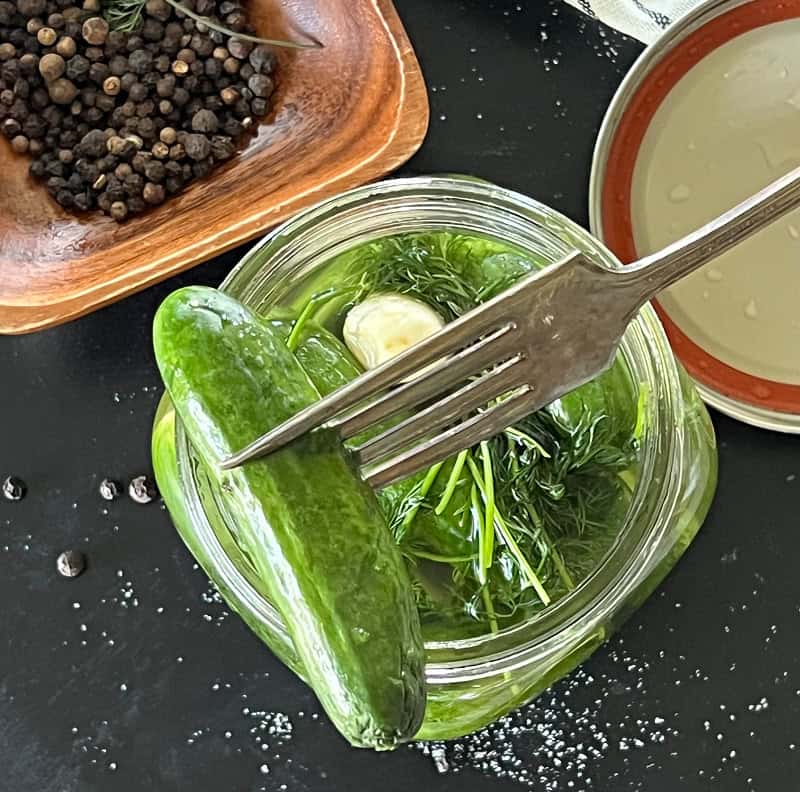 overhead view refrigerator dill pickles with fork spearing one pickle