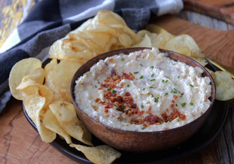 copper bowl with smoked gouda cheese dip garnished with bacon and surrounded by potato chips