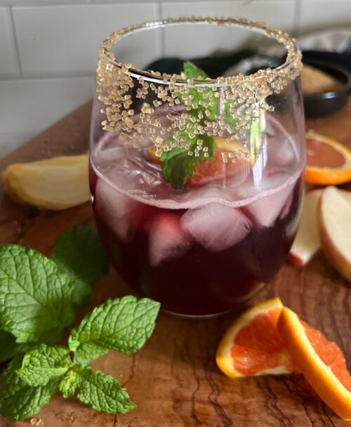 single glass of Thanksgiving sangria on a board with fresh mint leaves alongside it