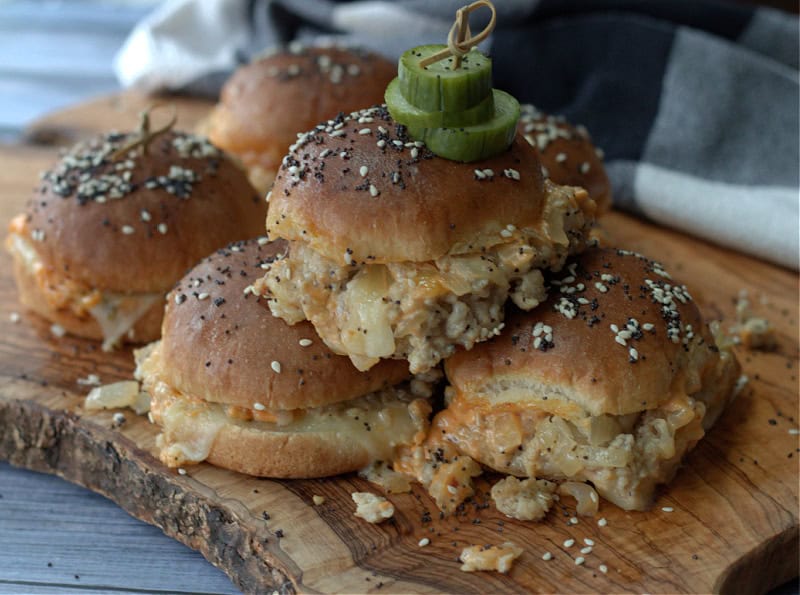 wood board with Turkey Burger Sliders piled on it plus pickle chips