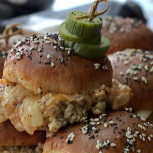 closeup of turkey burger sliders and pickle chips on a wood cutting board.