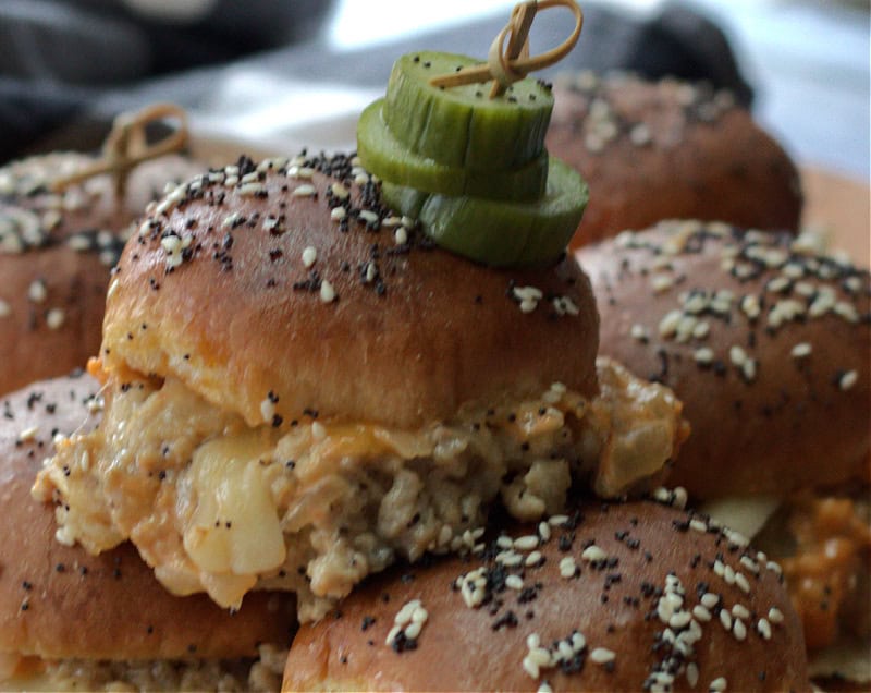 closeup of turkey burger sliders and pickle chips on a wood cutting board.