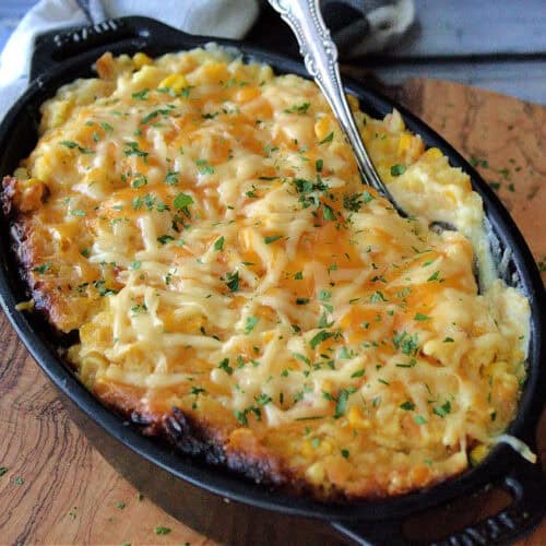 overhead view black serving dish with Crock Pot Corn Casserole and spoon scooping out