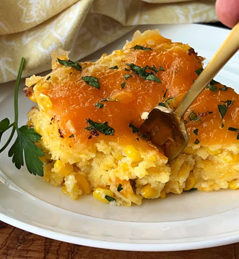 white plate with serving of crock pot corn casserole and fork inserted