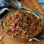 stainless steel baking dish with creamy mashed sweet potatoes topped with bacon and brown sugar crumble