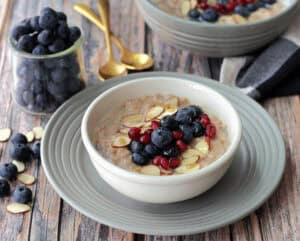 white bowl with slow cooker oatmeal topped with blueberries and pomengranate seeds
