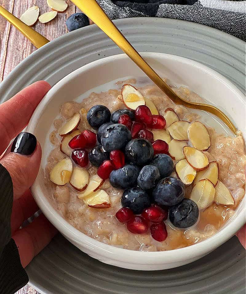 bowl of slow cooker oatmeal showing a hand on the side of the bowl