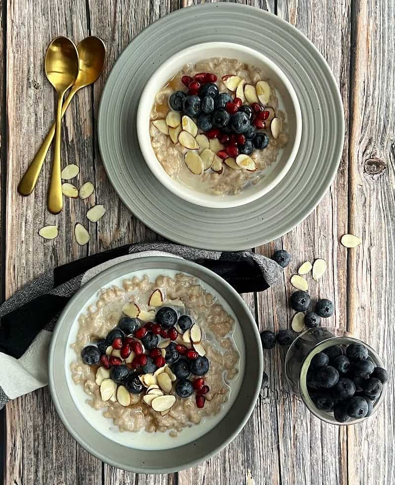overhead view of two bowls of slow cooker oatmeal topped with blueberries and pomegranate seeds