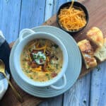 overhead view - white bowl with chilis baked potato soup garnished with extra cheese, sour cream and bacon